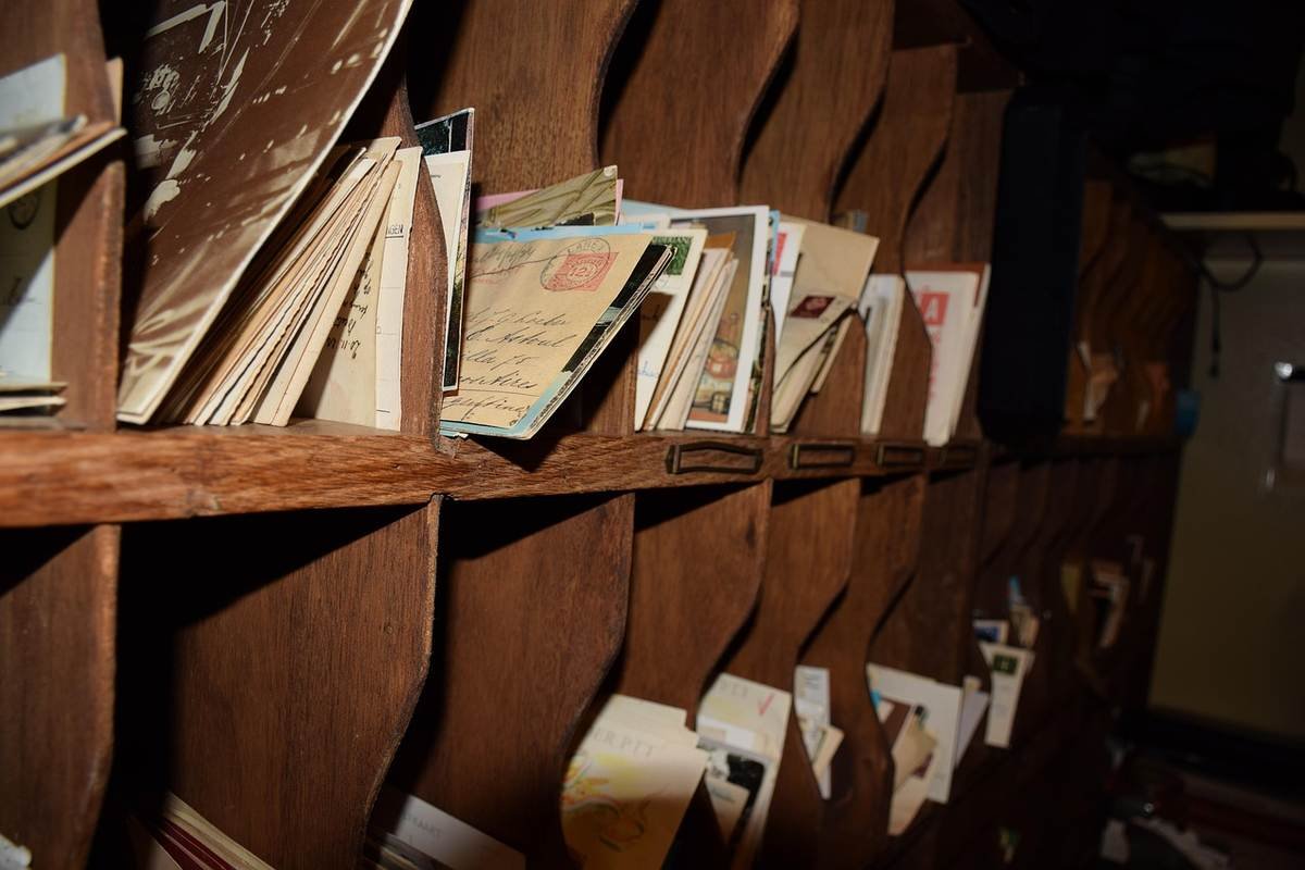 Des classeurs en bois remplis de dossiers et lettres dans une salle sombre