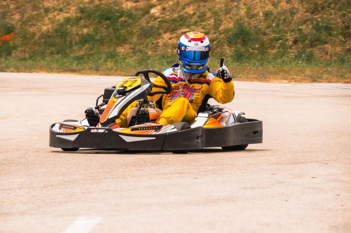 Un coureur de kart sur piste donne un signe de la main