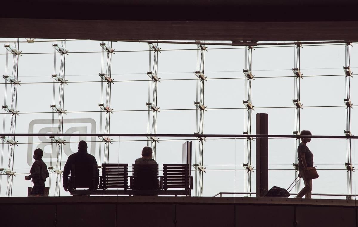 Silhouettes de personnes debout et assises devant une grande baie vitrée dans un espace professionnel lumineux Silhouettes de personnes debout et assises devant une grande baie vitrée dans un espace professionnel lumineux