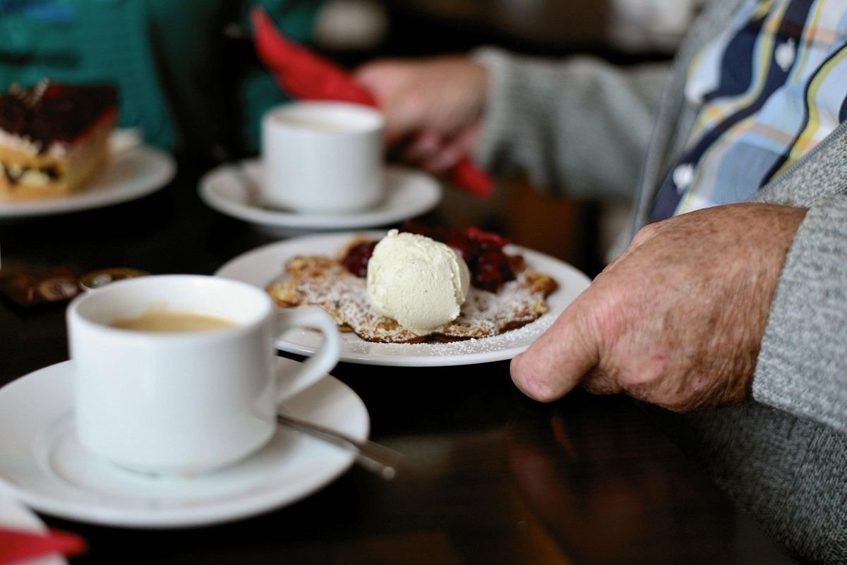 Tasses de café, assiette avec gâteau et glace, mains d'une personne Tasses de café, assiette avec gâteau et glace, mains d'une personne