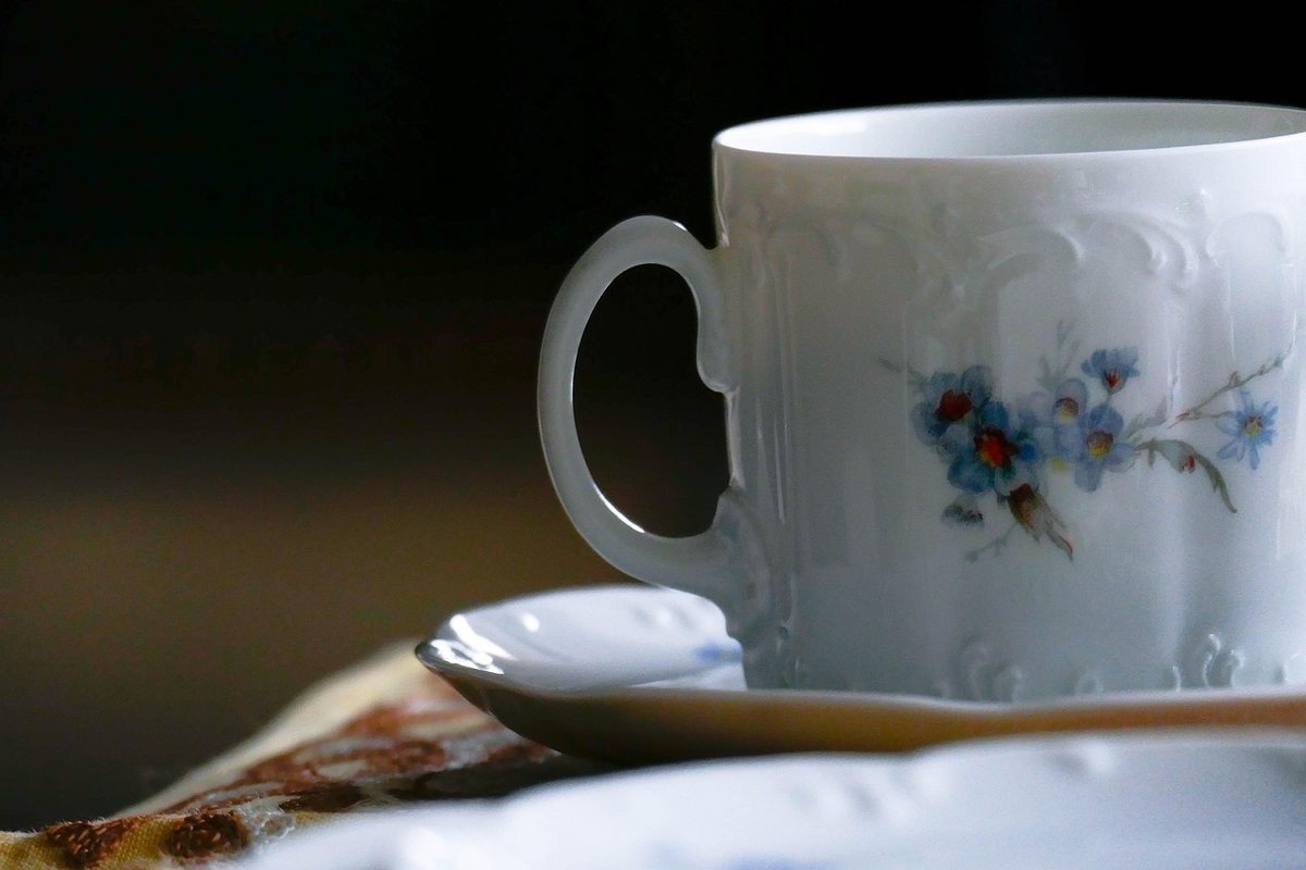 Tasse blanche décorée de fleurs bleues posée sur un plateau