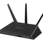 Un routeur Netgear noir à trois antennes posé sur fond blanc