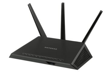 Un routeur Netgear noir à trois antennes posé sur fond blanc
