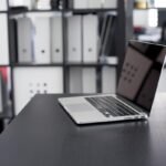 Un ordinateur portable ouvert repose sur un bureau sombre