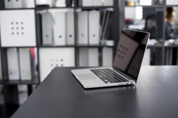 Un ordinateur portable ouvert repose sur un bureau sombre