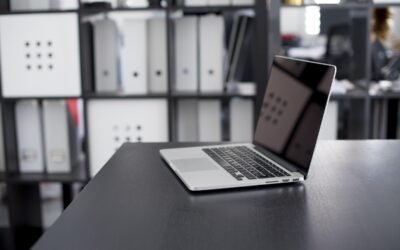 Un ordinateur portable ouvert repose sur un bureau sombre